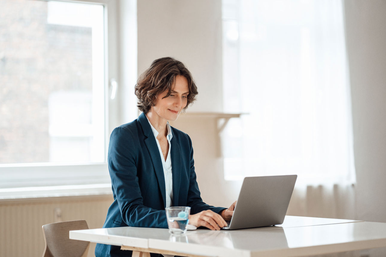 Frau sitzt am Laptop in einem hellen Büro