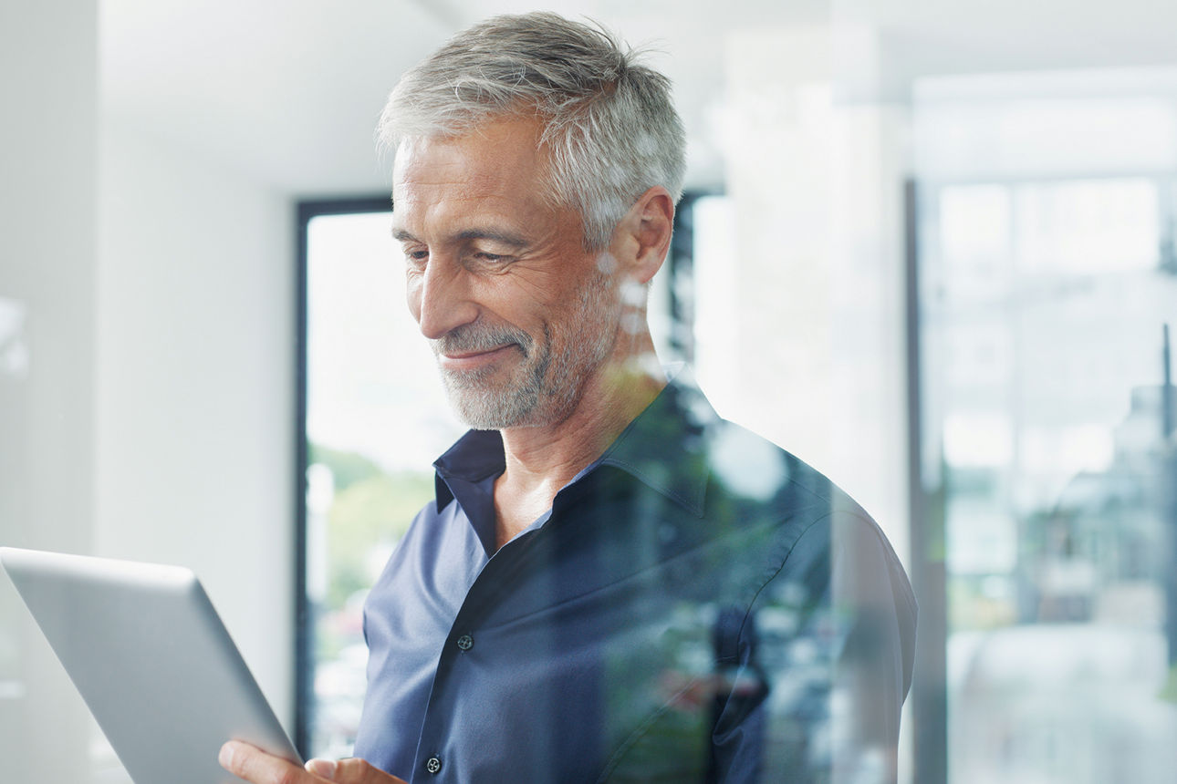 Mann mit Tablet in der Hand hinter einer Scheibe