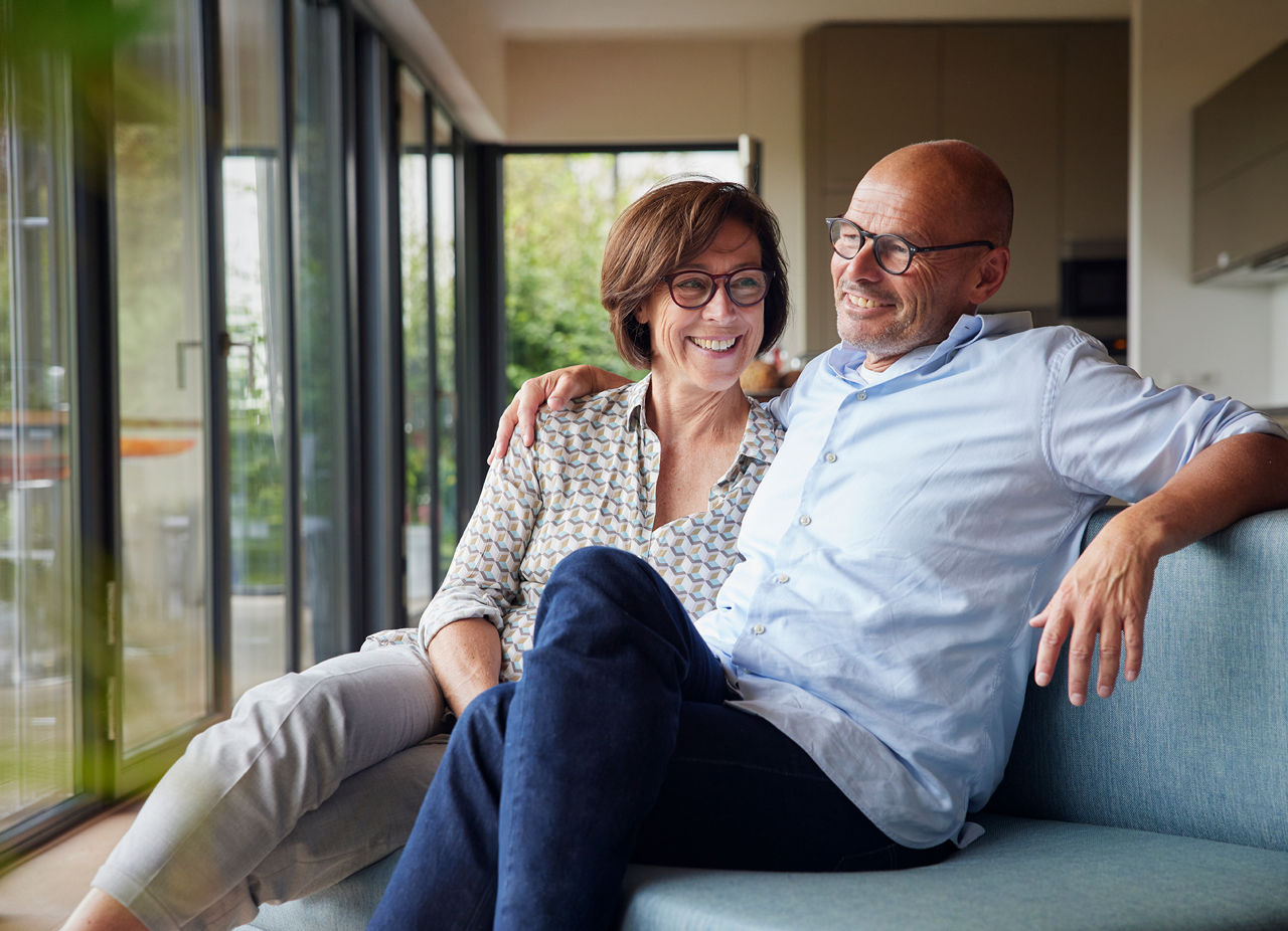 Ehepaar sitzt im Wohnzimmer auf der Couch.