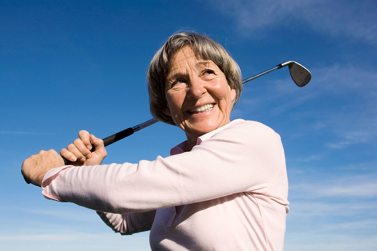Älterere Frau spielt Golf