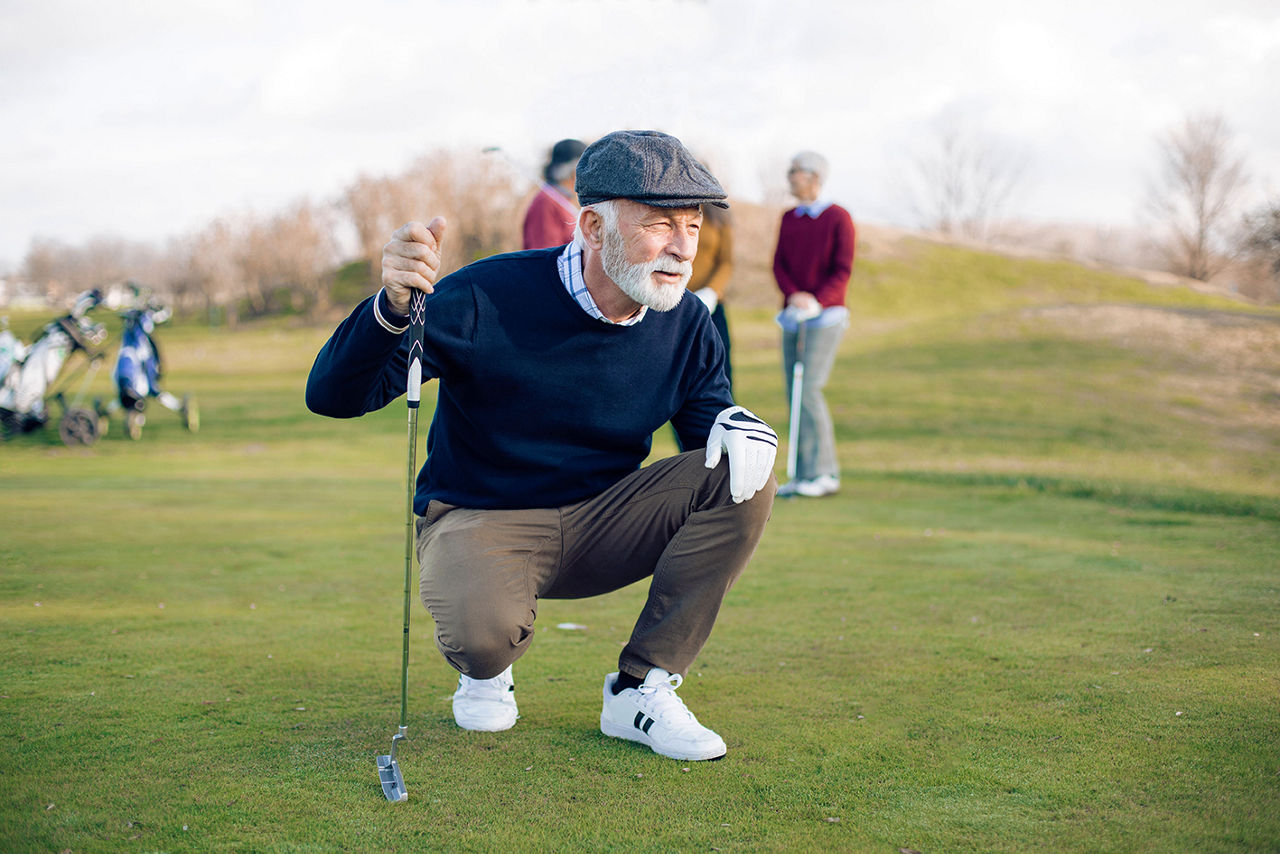 Älterer Mann spielt mit seinen Freunden Golf