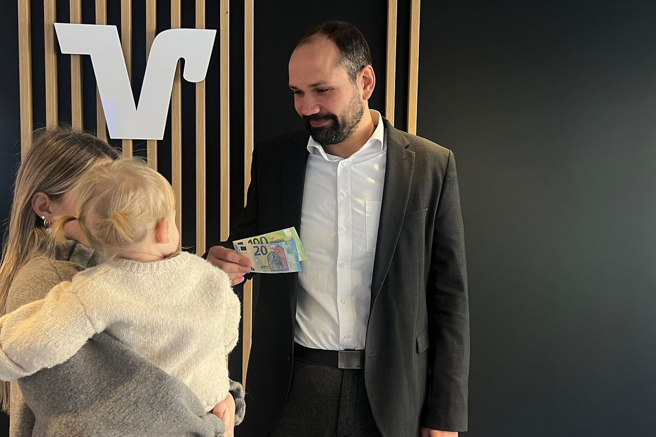 Eine Frau mit kleinem Kind auf dem Arm schauten zu einem Mann mit 120 € in der Hand.