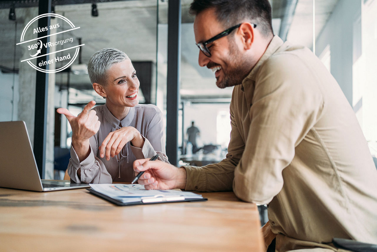 Aufnahme von zwei selbstbewussten Geschäftsleuten, die an einem Schreibtisch im Büro sitzen und Ideen austauschen. Ein Geschäftsmann und eine Geschäftsfrau besprechen in einem Meeting mithilfe von Laptops ihre Geschäftsstrategie. Geschäftspartner arbeiten im Büro zusammen.