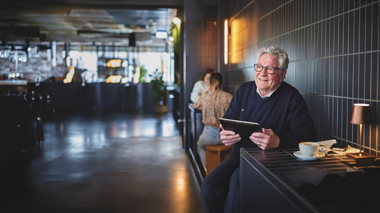 Senior im Café mit einem Tablet in der Hand