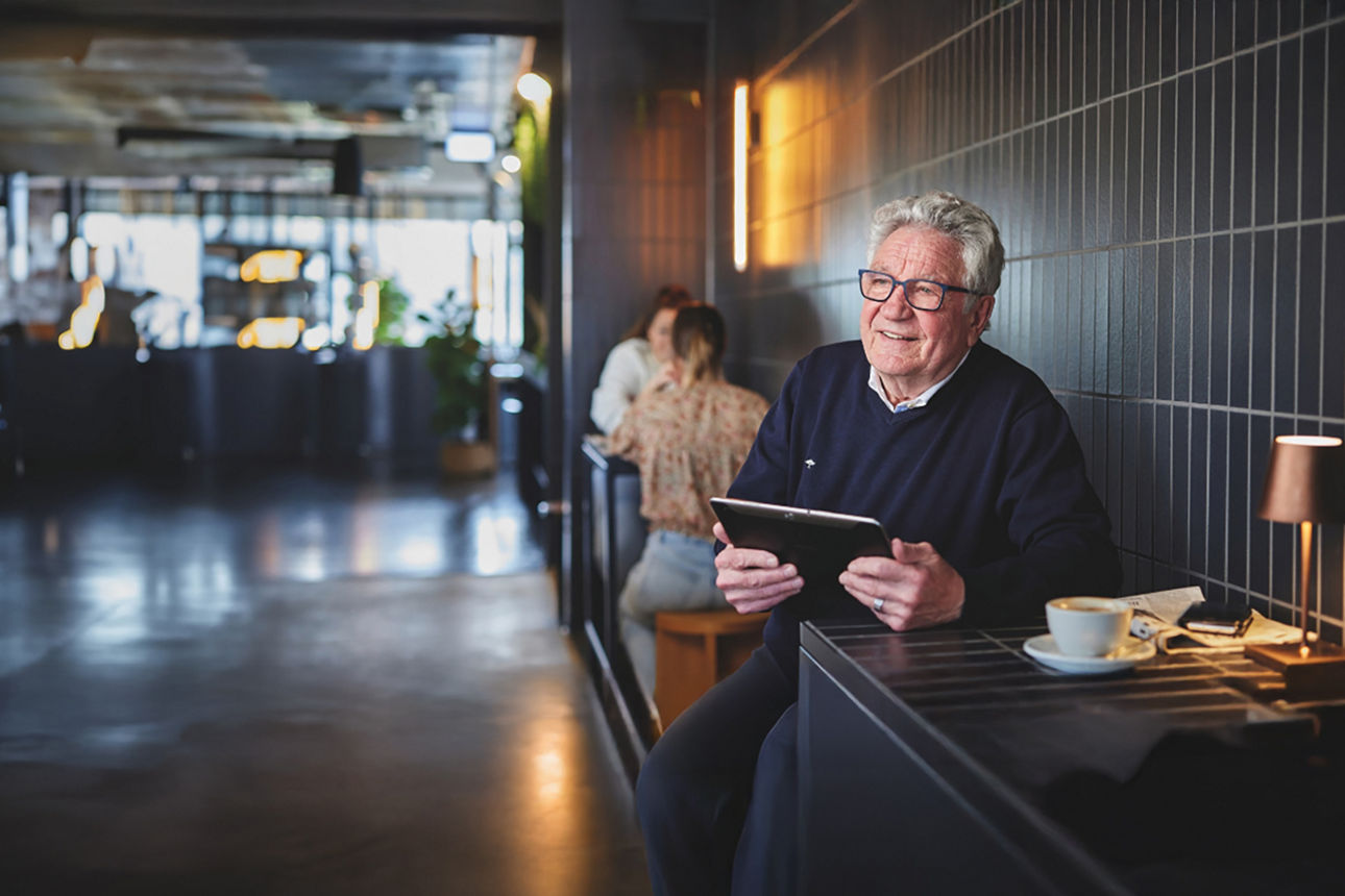 Senior im Café mit einem Tablet in der Hand