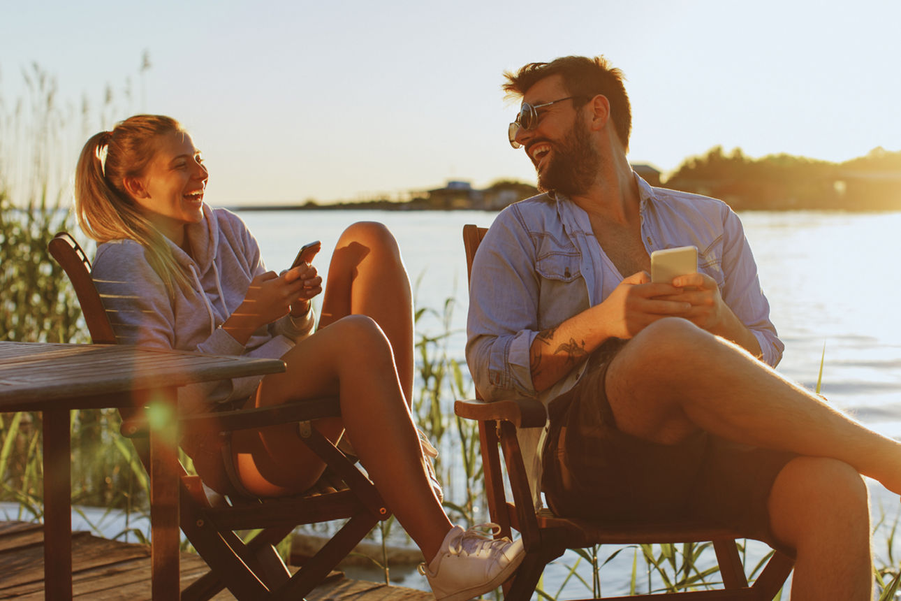 Young woman and man using smartphone by the river