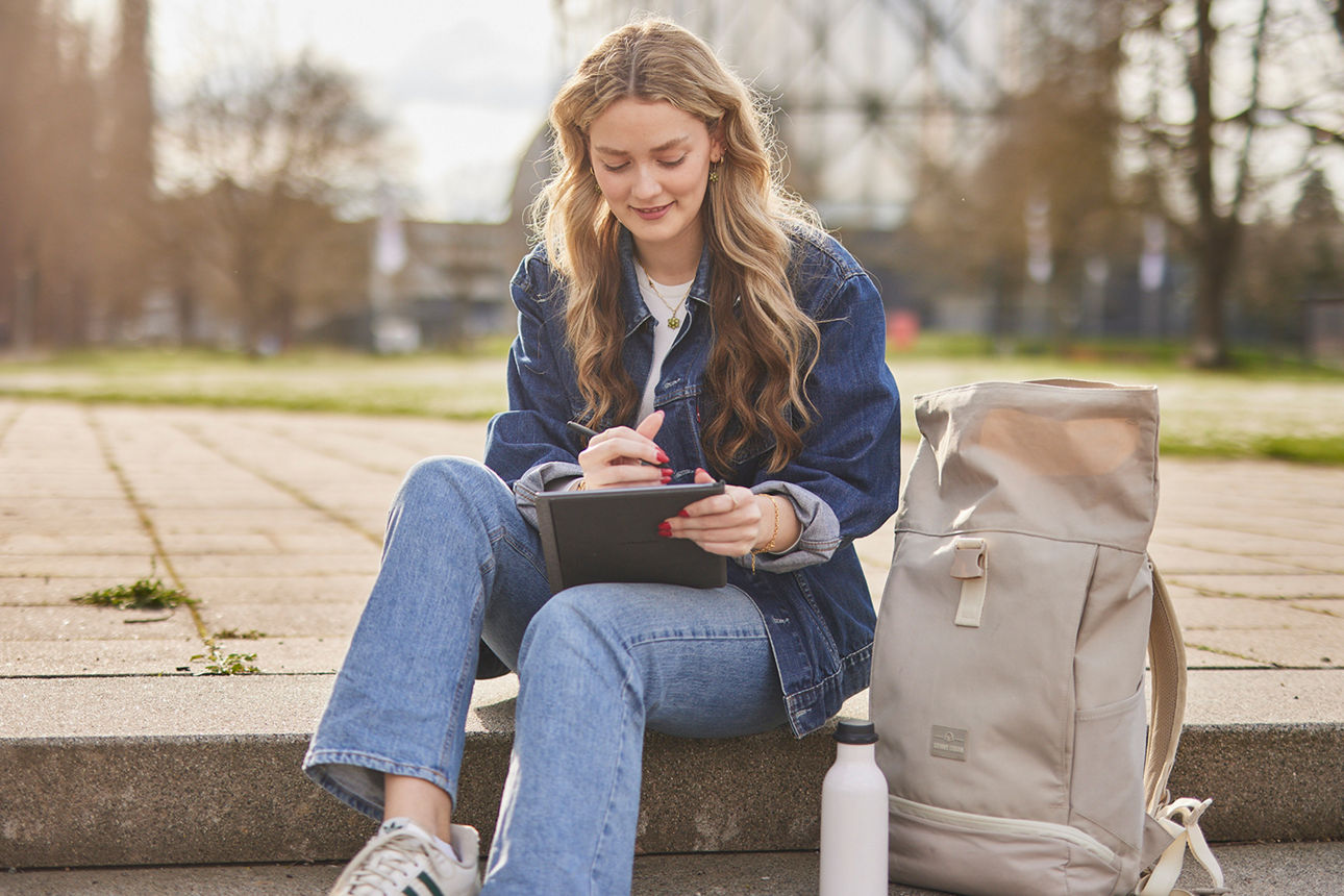 Studentin macht sich Notizen sitzend auf einer Stufe