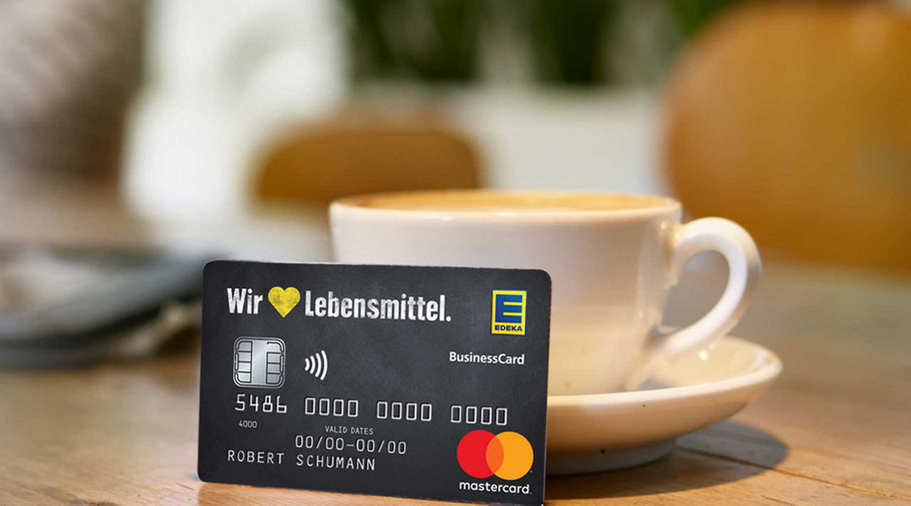 Eine EDEKA-Marstercard steht angelehnt an einer Kaffeetasse