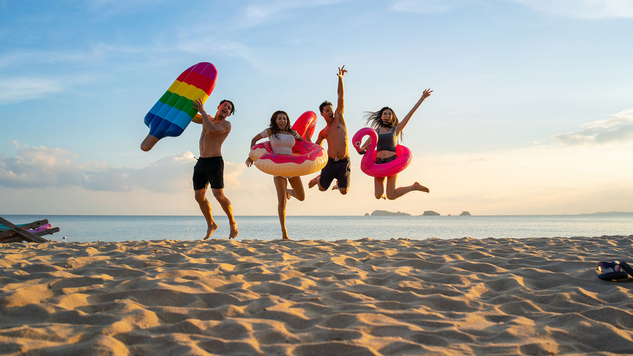Familie mit zwei Kinder springen fröhlich am Strand in die Luft