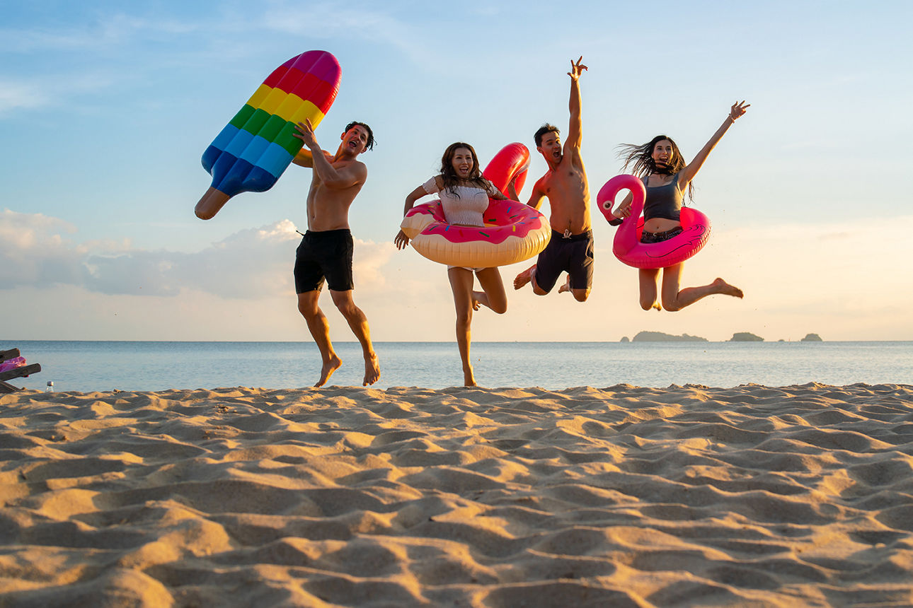 Familie mit zwei Kinder springen fröhlich am Strand in die Luft