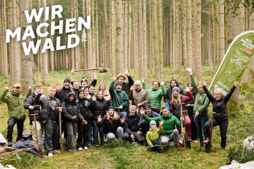 Ein Gruppe von Baumpflanzern im Wald unter dem Motto "Wir machen Wald"
