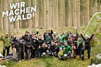 Gruppe von Menschen, die freudig lächelnd im Wald zusammenstehen
