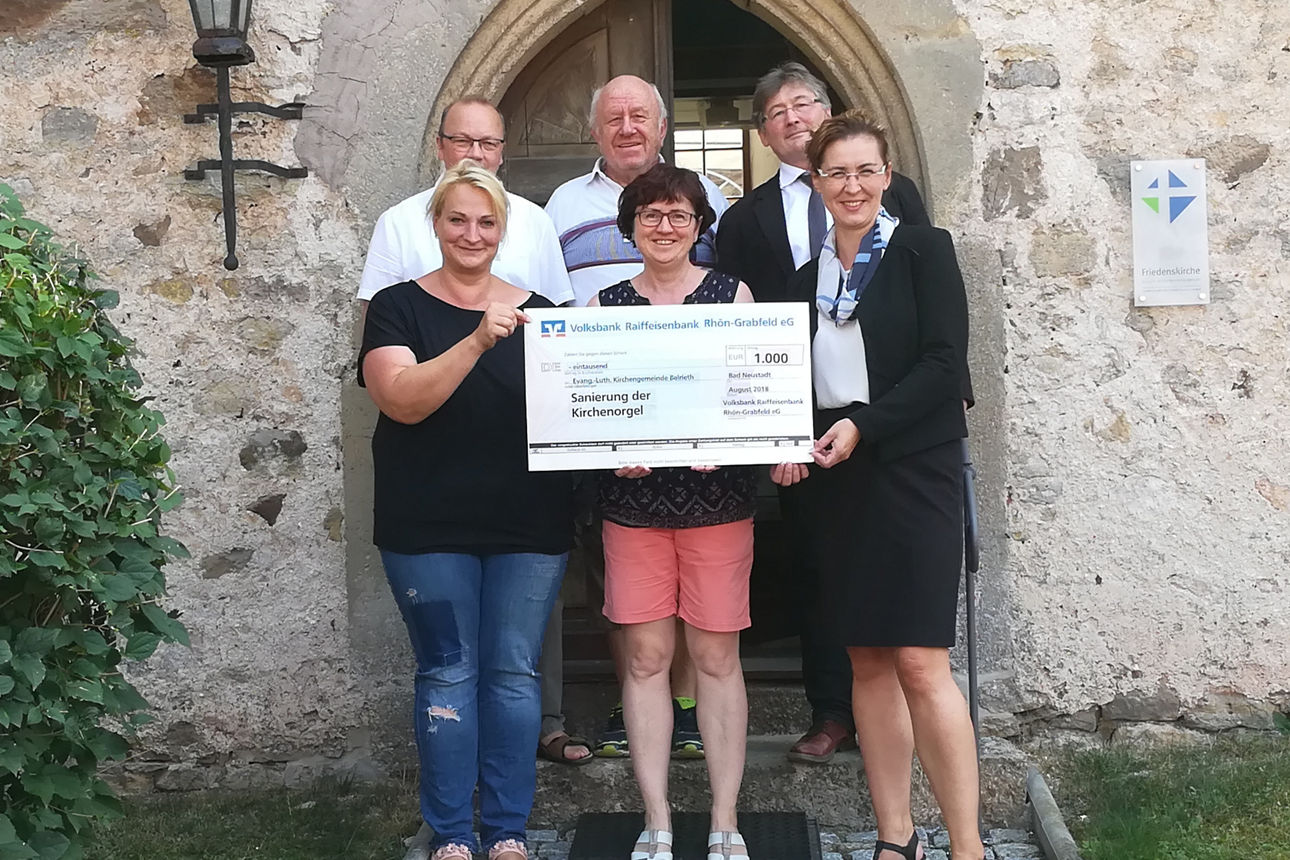 Drei Männer und drei Frauen stehen vor einem Kircheneingang 