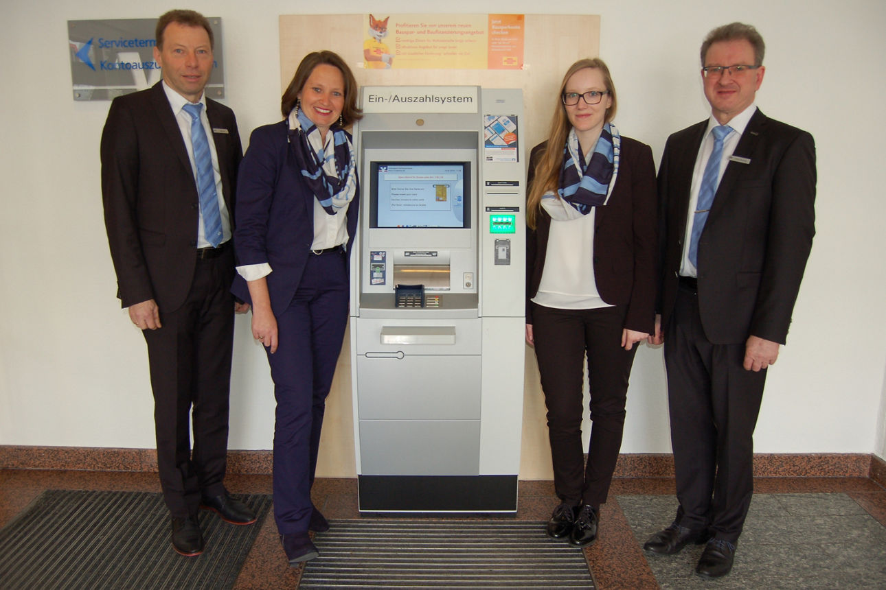 Zwei Männer und zwei Frauen stehen neben einem Geldautomaten 
