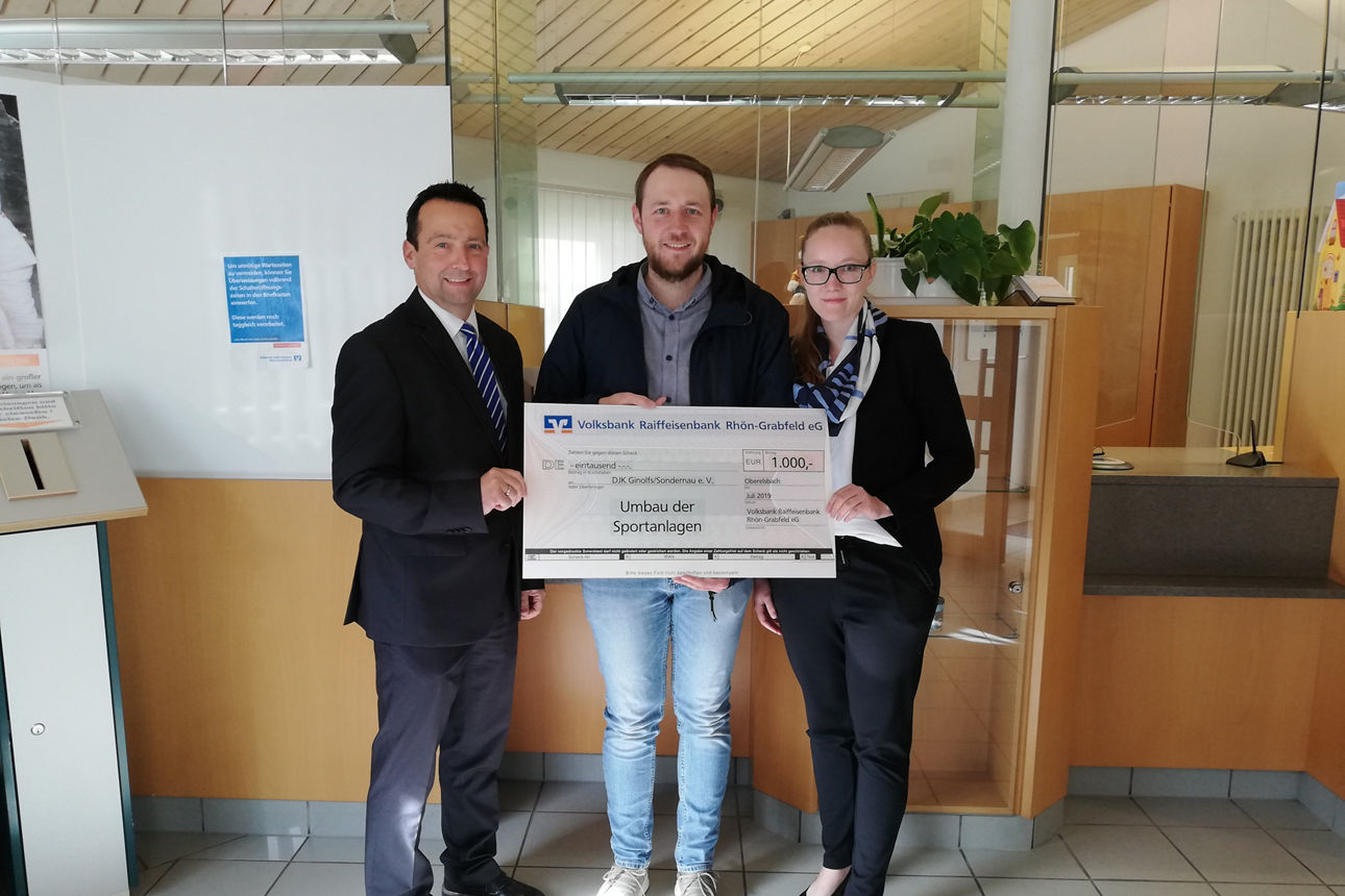 Zwei Männer und eine Frau halten einen Spendenscheck in der Hand