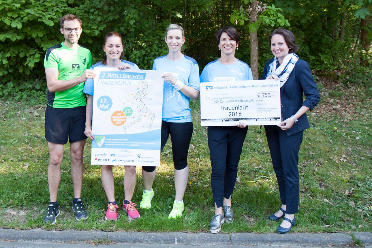 Vier Frauen und ein Mann stehen vor einem Wald und halten ein Plakat, sowie einen Spendenscheck in der Hand