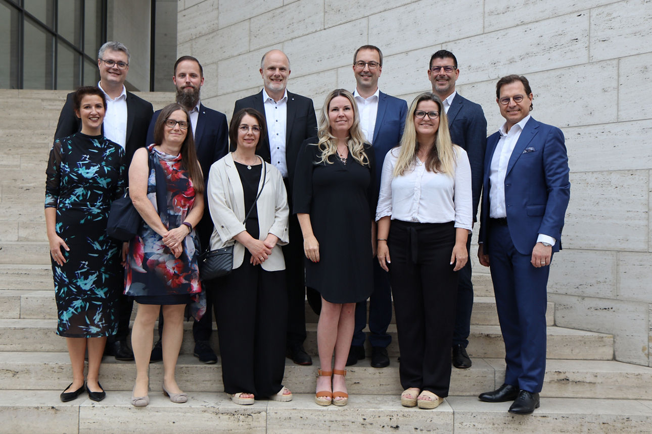 Viele festlich gekleidete Menschen stehen auf einer Treppe in zwei Reihen 