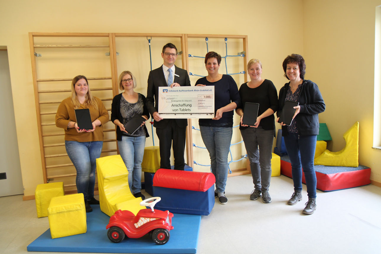 Fünf Frauen und ein Mann stehen vor einer Klettersprosse und zwei von Ihnen halten einen Spendenscheck in der Hand 