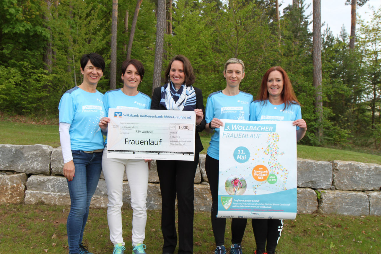 Fünf Frauen stehen vor einer Steinmauer und halten zwei Plakate in den Händen.