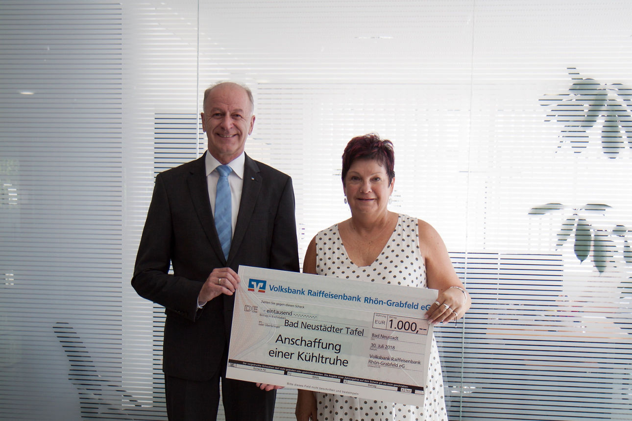 Ein Mann und eine Frau halten einen Spendenscheck in der Hand 