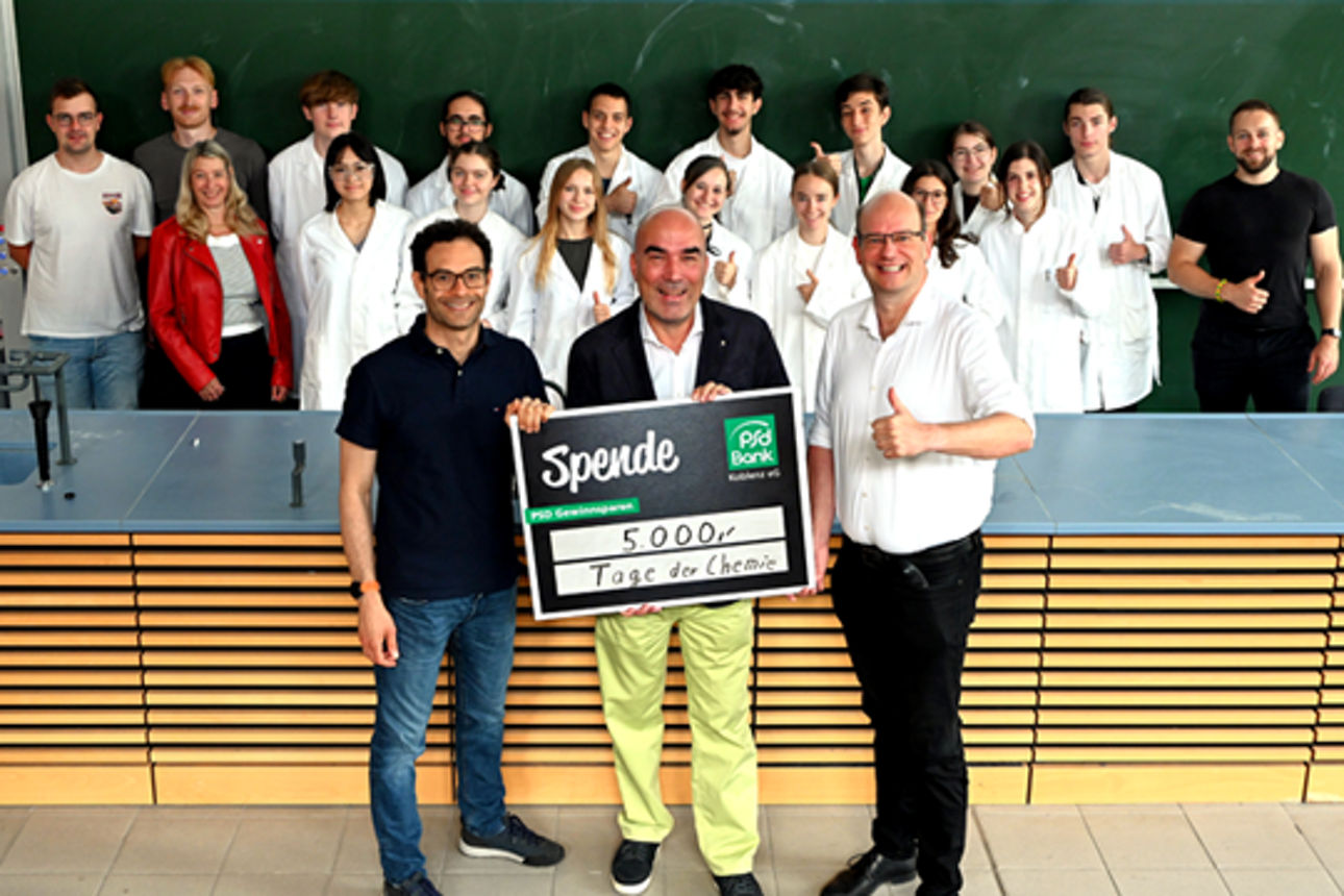 Eine Gruppe Personen posiert mit einem Spendenscheck
