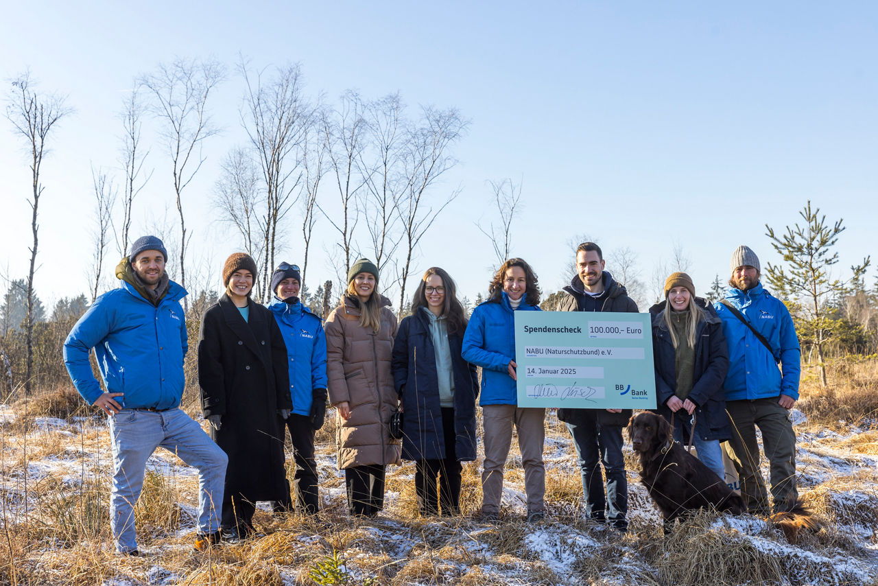 Personen stehen mit Spendenscheck  im Arrisrieder Moos