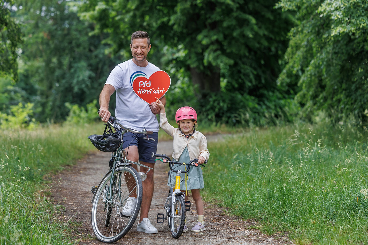 Vater und kleine Tochter stehen mit dem Fahrrad auf einem Weg in der Natur.