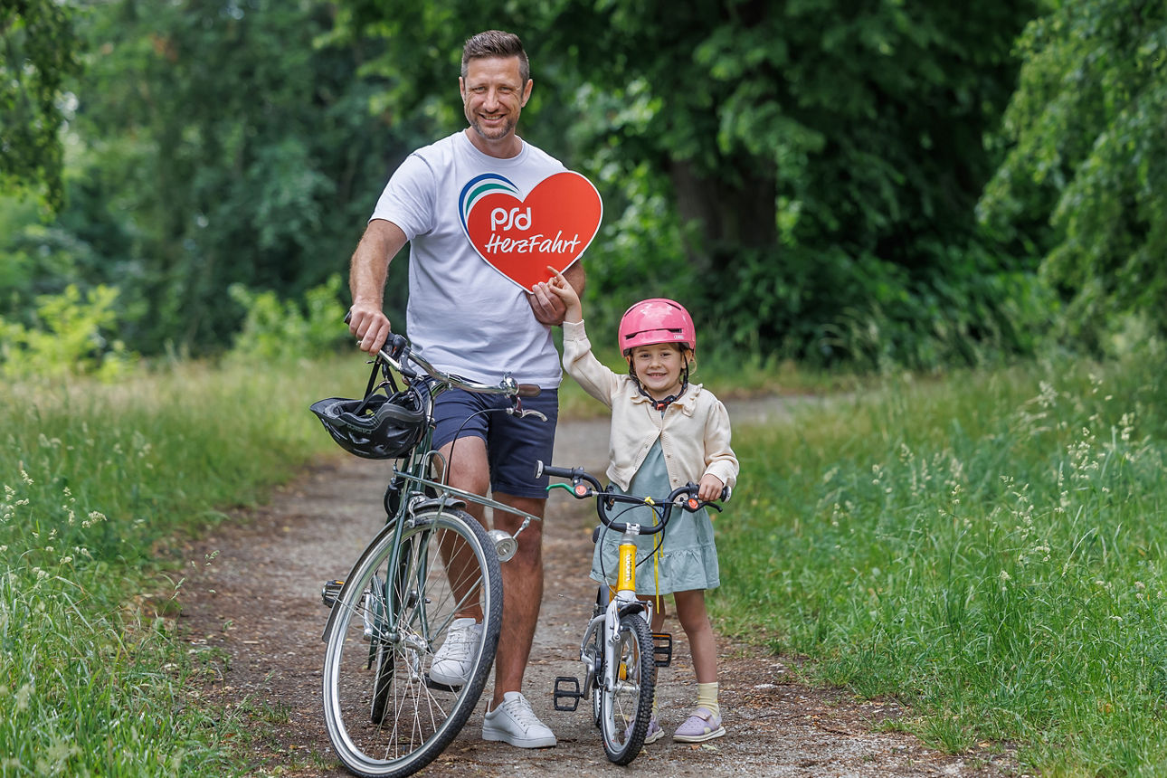 Vater und kleine Tochter stehen mit dem Fahrrad auf einem Weg in der Natur.