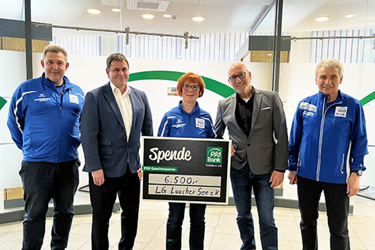 Eine Gruppe Personen posiert mit einem Spendenscheck
