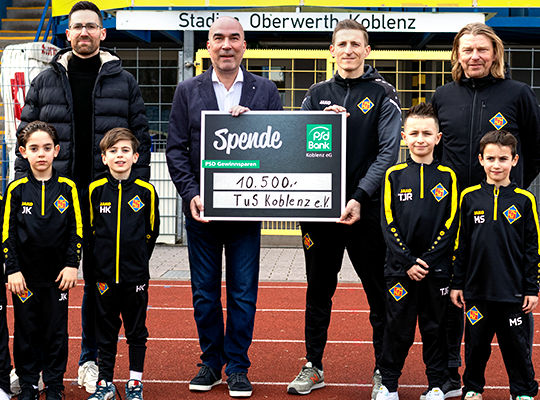 Eine Gruppe junger Fußballer posiert zur Spendenübergabe mit dem Vorstand der PSD Bank Koblenz
