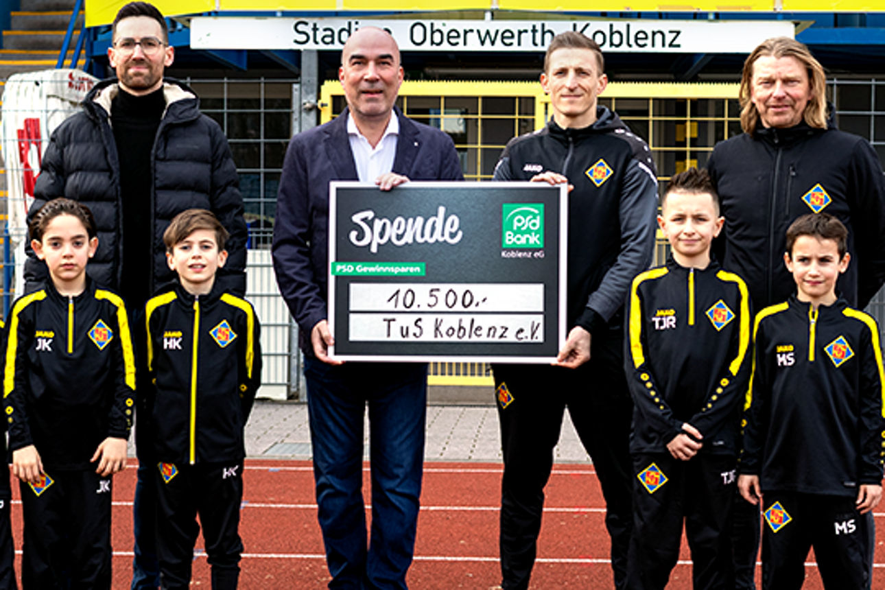 Eine Gruppe junger Fußballer posiert zur Spendenübergabe mit dem Vorstand der PSD Bank Koblenz