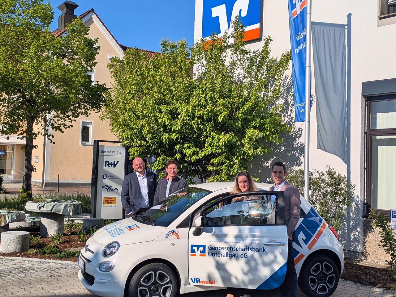VRmobil Auto wird vor der Bank in Bad Wörishofen der Ambulanten Krankenpflege übergeben