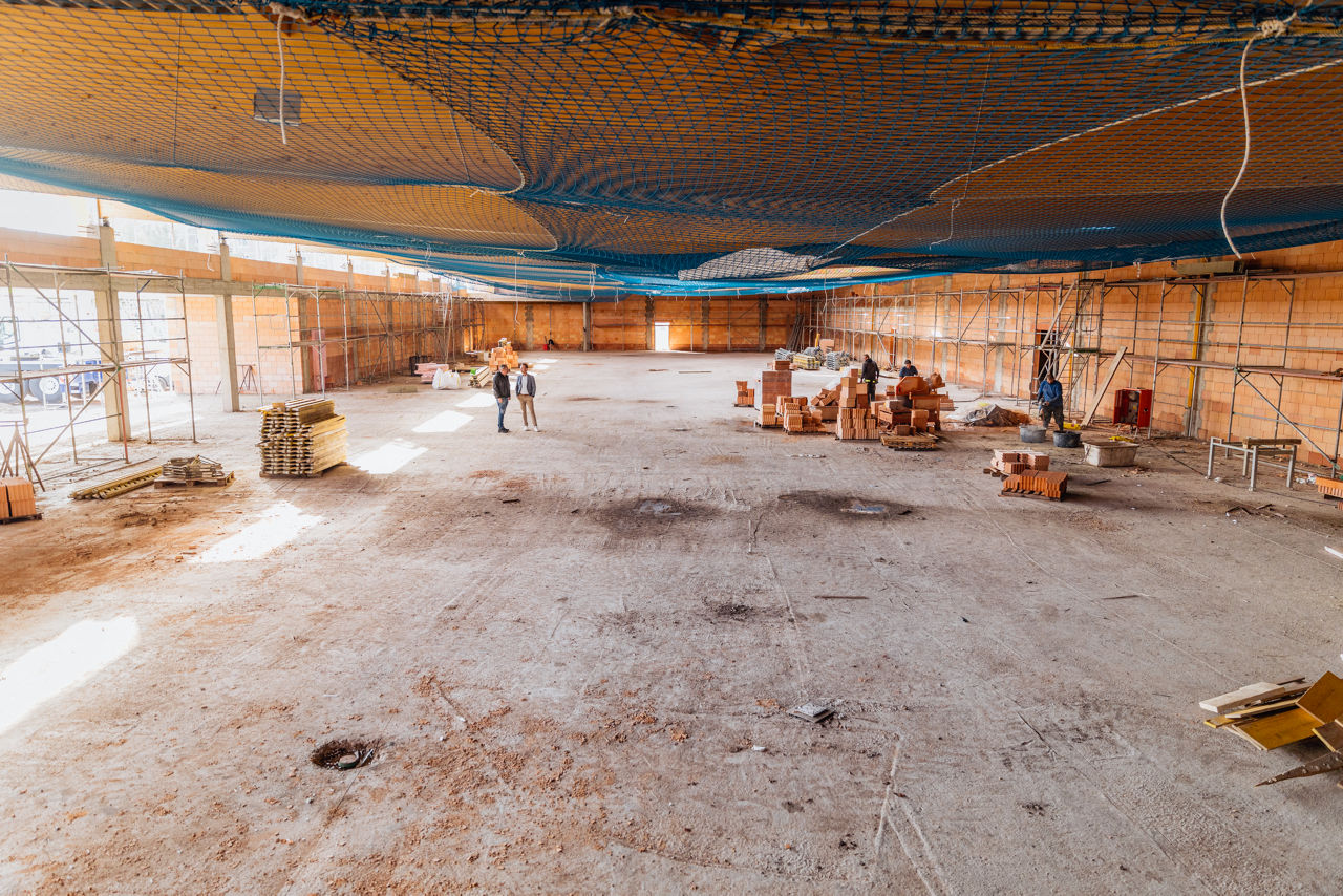Weitläufige Innenansicht einer Rohbauhalle eines Projekts von „PZ Marktbau“ mit offenen Bodenflächen und vereinzelten Baustellenmaterialien, aufgenommen während der laufenden Bauphase