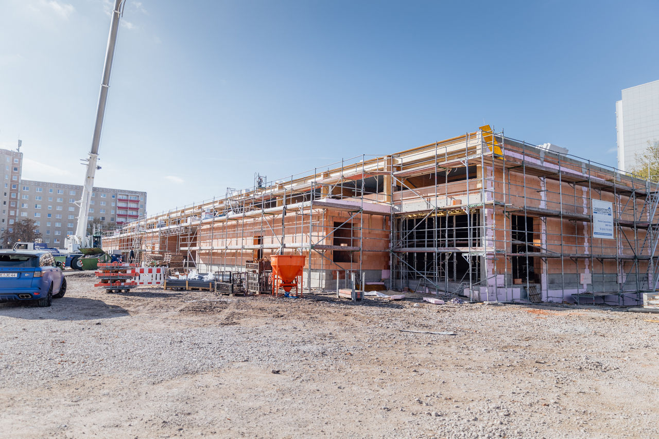 Außenansicht eines im Rohbau befindlichen Fachmarktzentrums eines Projekts von „PZ Marktbau“ mit sichtbaren Gerüsten, Mauerwerk und laufenden Bauarbeiten im Bereich der Gebäudehülle