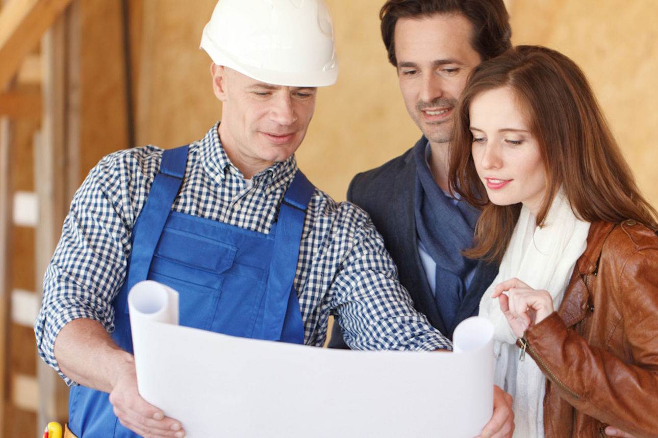 Bauarbeiter zeigt einem Paar Baupläne