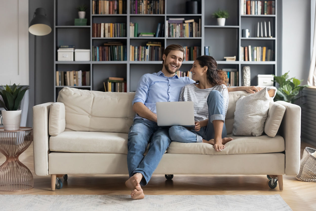 Mann und Frau sitzen mit einem Laptop auf einem Sofa