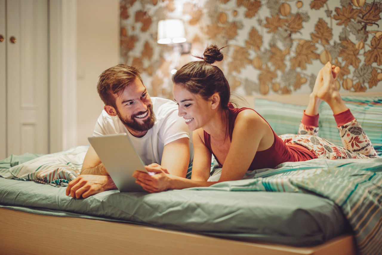 Young african woman holding home keys while hugging boyfriend in their new apartment after buying real estate. Lovely girl holding keys from new home and embracing man. Happy couple in their apartment around cardboard boxes.