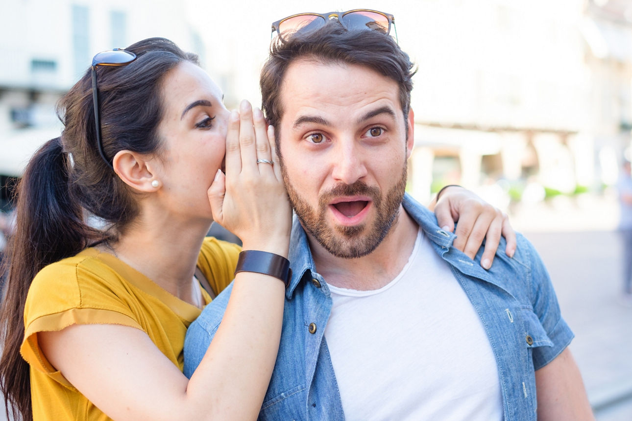 Frau flüstert ihrem Freund ins Ohr