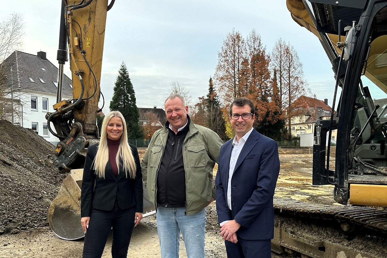 v.l.n.r.: Karoline Dlugosch, Olaf Klüsener und Andreas Furmaniak stehen vor einem Bagger auf der Baustelle