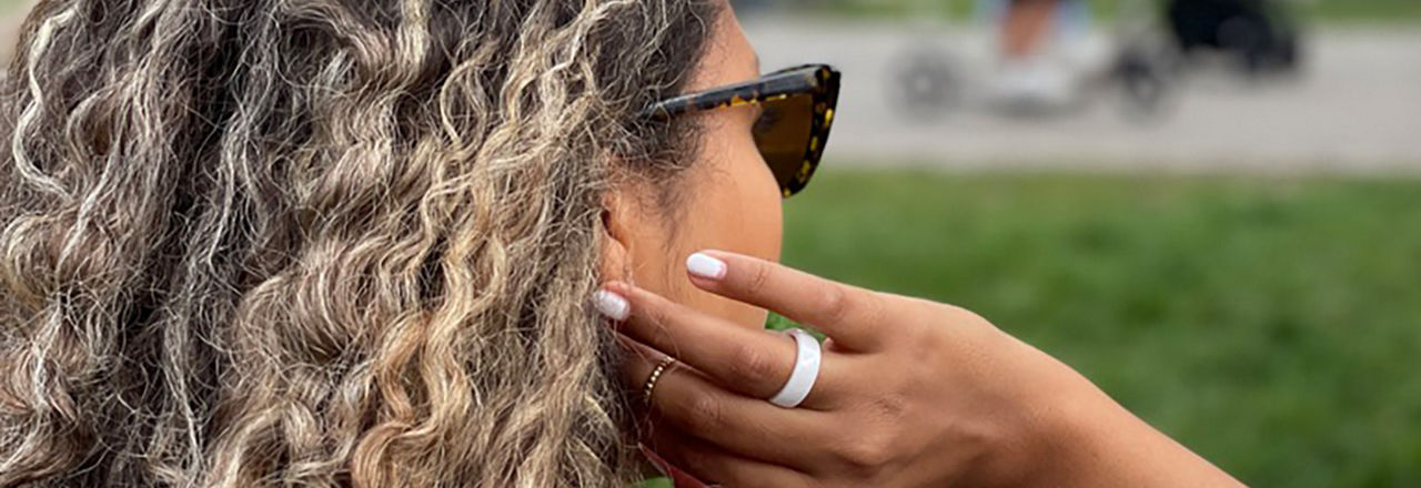 Frau mit Locken fasst sich mit der Hand ins Haar mit einem Ring am Ringfinger