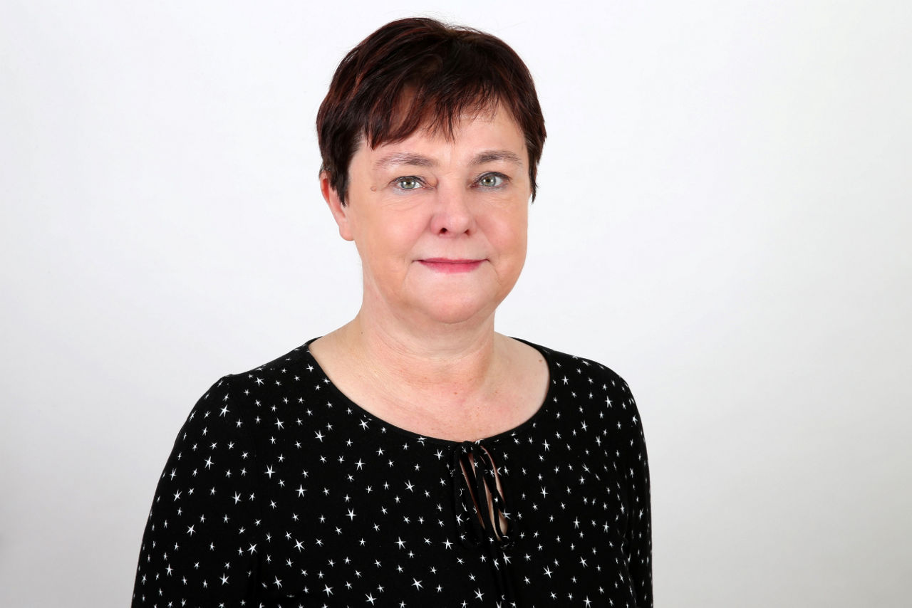 Eine lächelnder Frau schaut in die Kamera.