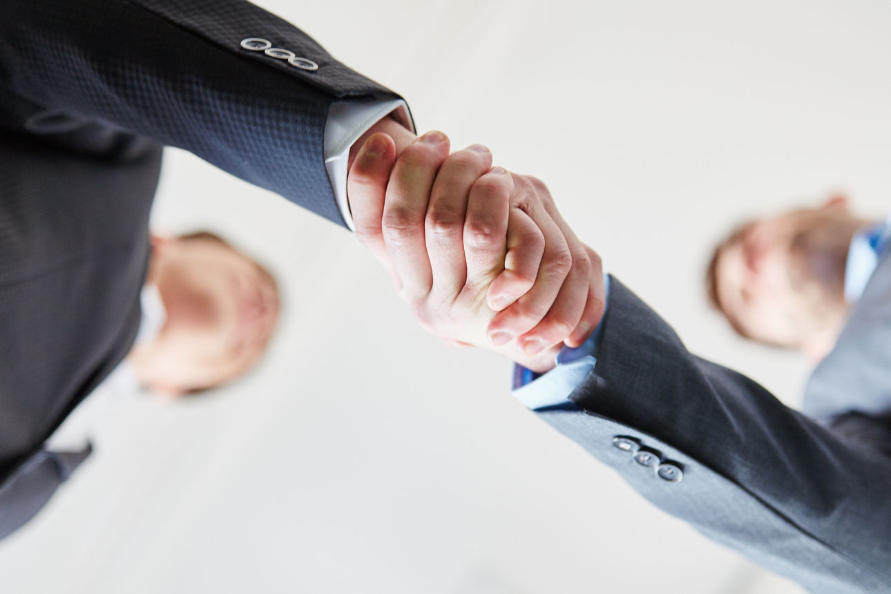 Zwei Männer im Anzug schütteln sich die Hand