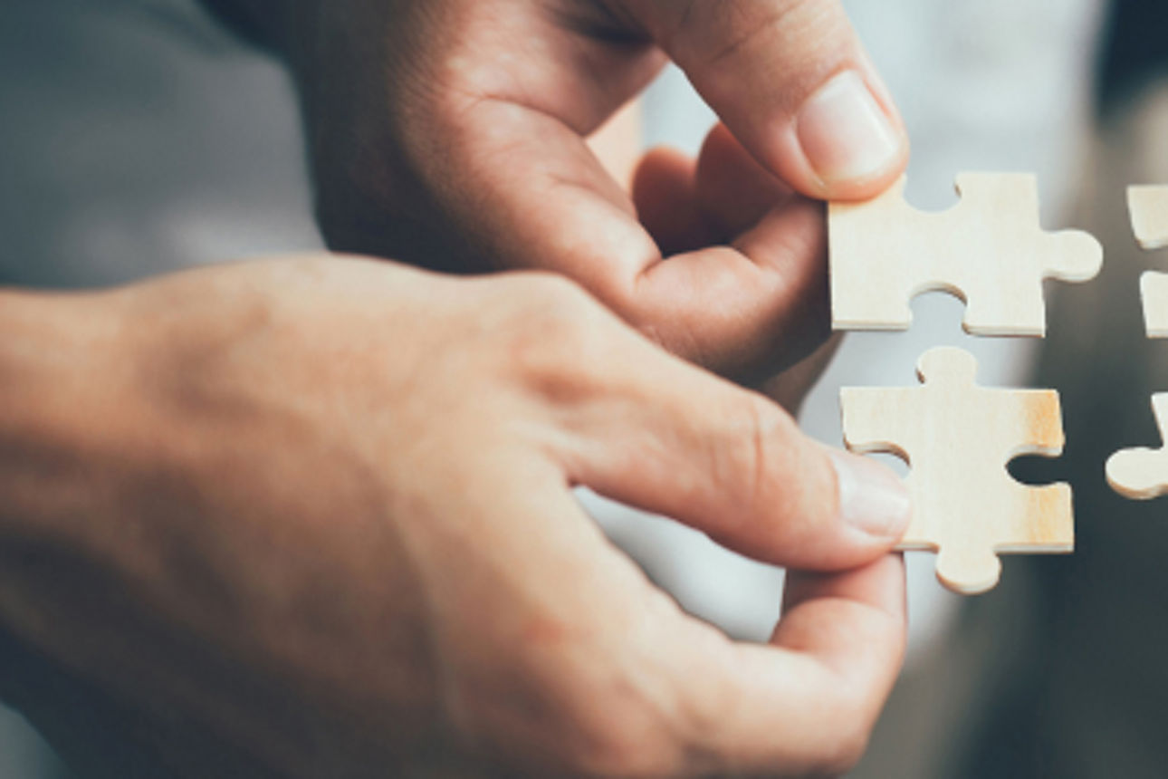 Vier Hände mit jeweils einem Puzzelstück