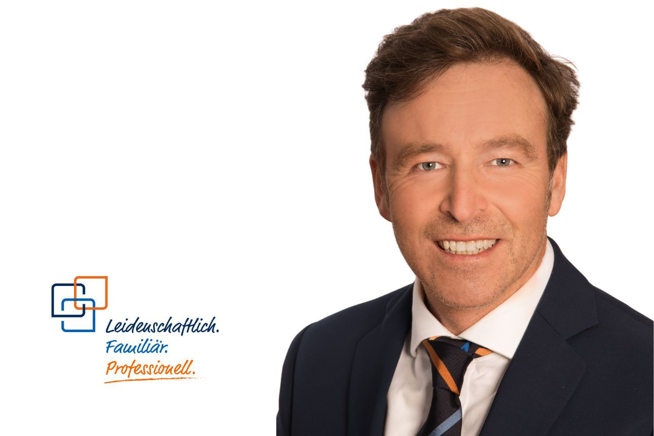 Porträt von Paul Kinigadner, einem lächelnden Mann im blauen Anzug mit gestreifter Krawatte. Daneben das Firmenlogo und der Slogan "Leidenschaftlich. Familiär. Professionell."