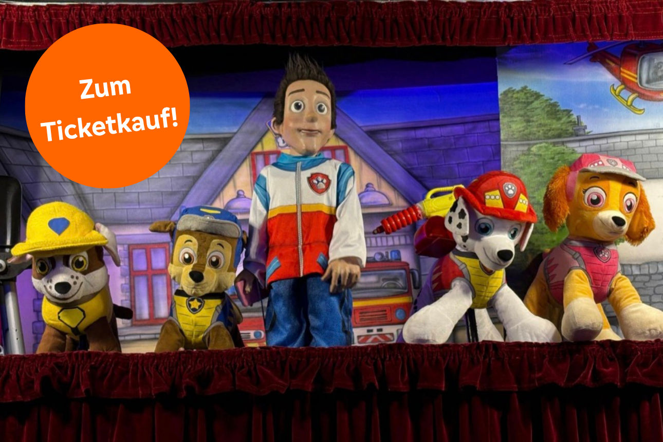 Foto: Theaterbühne, 4 Hundepuppen und eine Menschenpuppe - Text: "Zum Ticketkauf!"