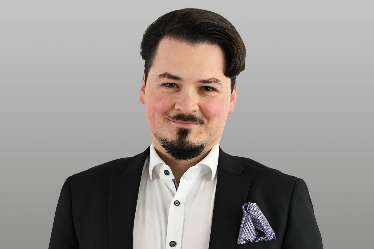 Kundenberater Vincent Peltzer vor grauen Hintergrund