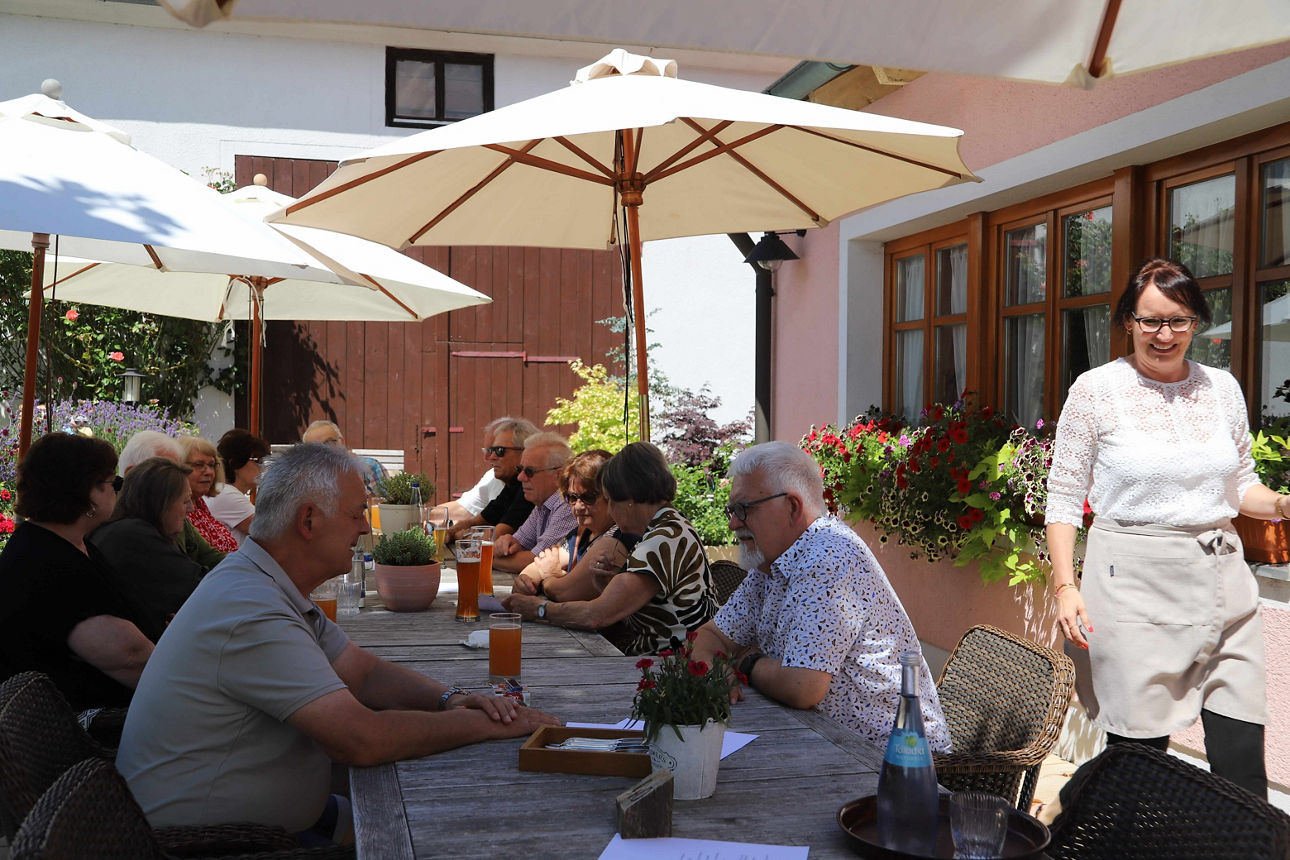 Pensionäre sitzen gemeinsam am Tisch eines Biergartens.