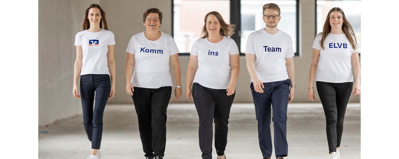 Unsere Personalabteilung steht lächelnd in Volksbank T-Shirts vor einer weißen Wand