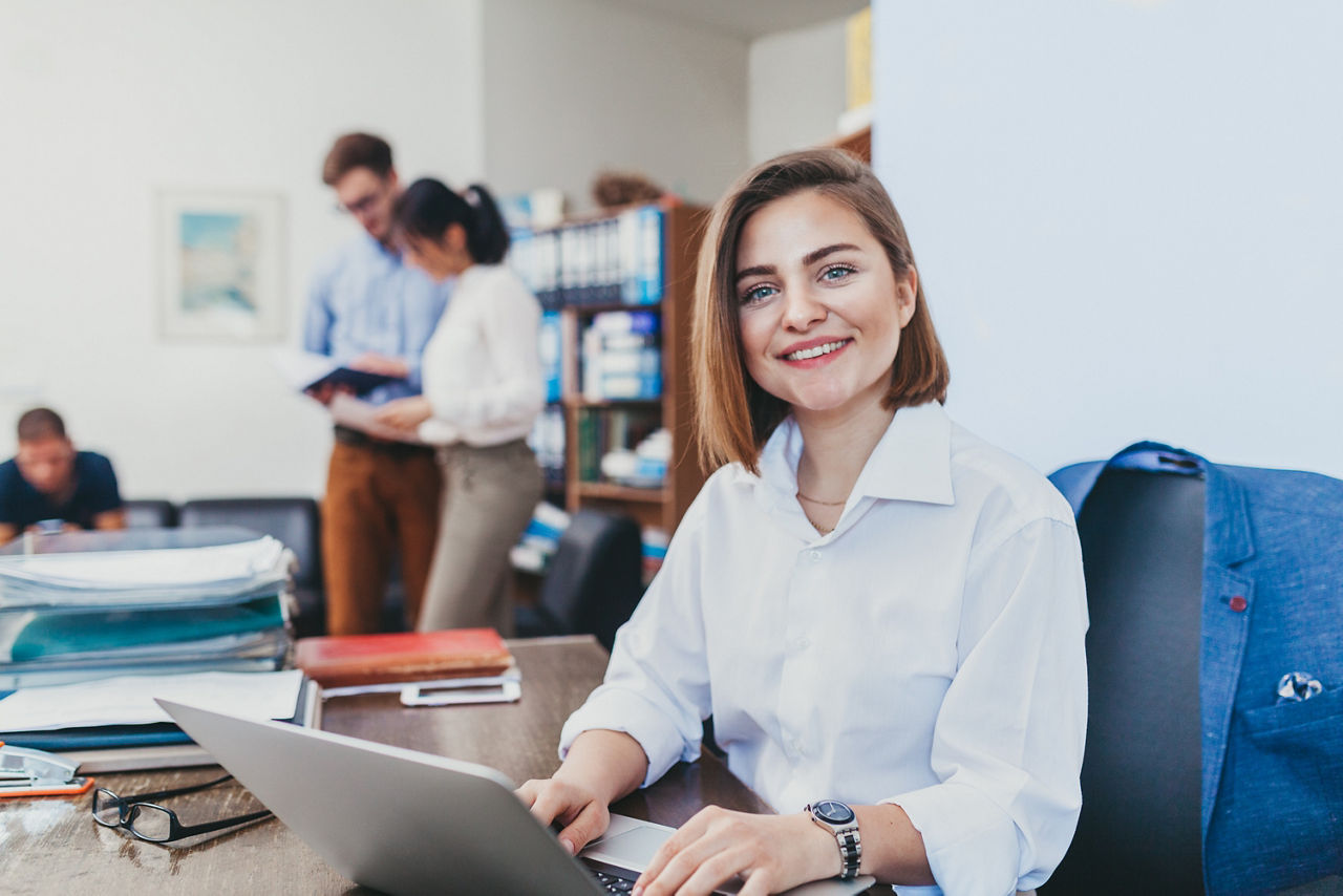 Frau lächelnd im Büro am Laptop