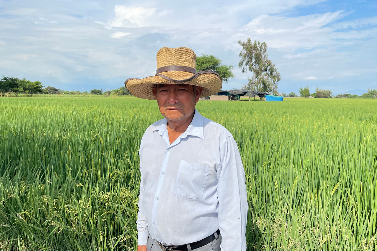 Mann mit Hut steht vor einem Feld und schaut in die Kamera